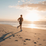 Young man training on the beach in morning. Young man on morning run outdoors
