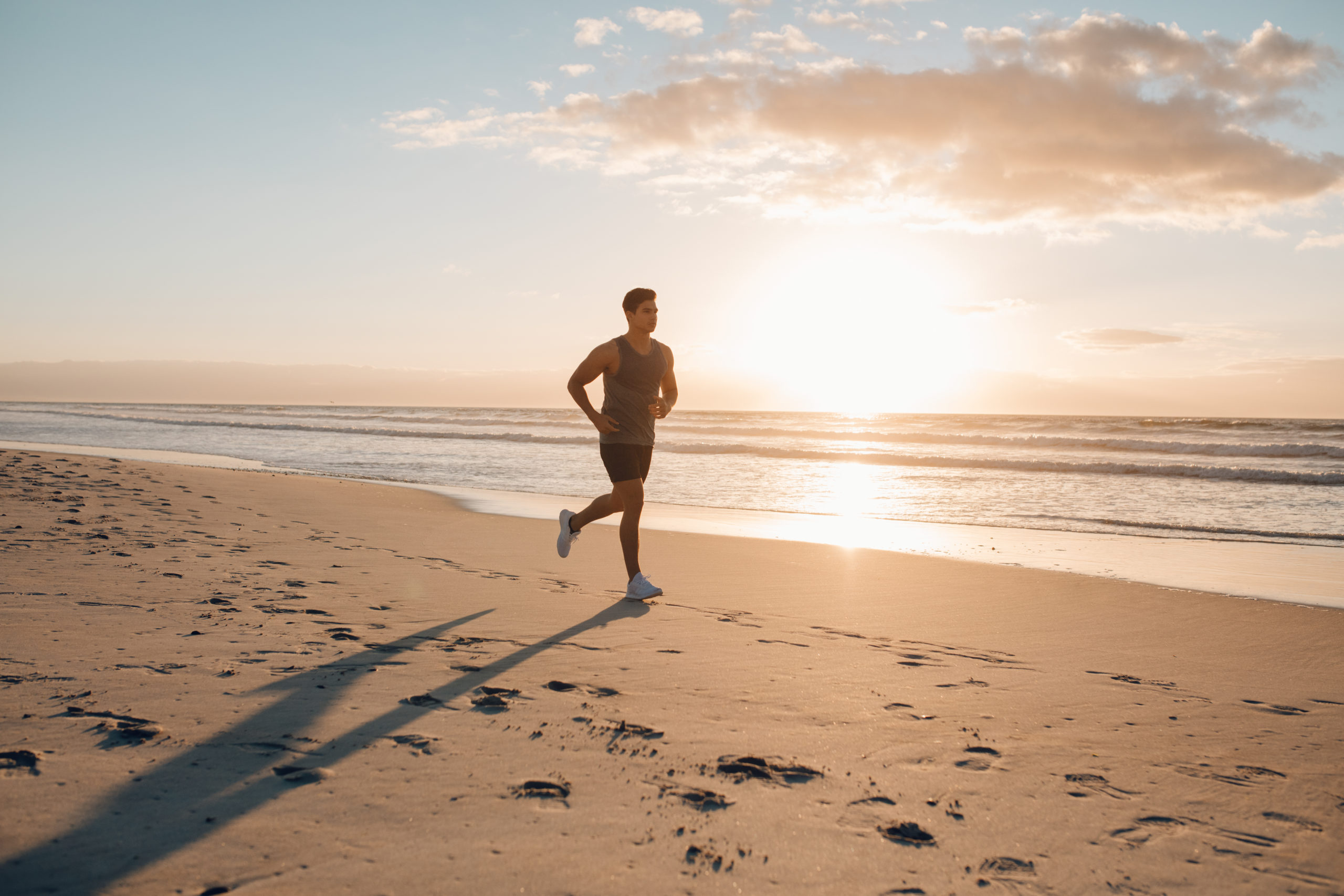 Young man training on the beach in morning. Young man on morning run outdoors