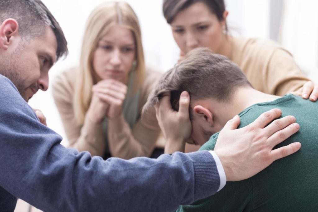 a young man with some family members feeling down and sad during an intervention