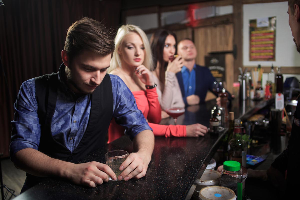 photo of a man drinking wine in the bar with two women and a man around him