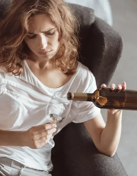 photo of unhappy young woman sitting on a sofa and drinking alcohol