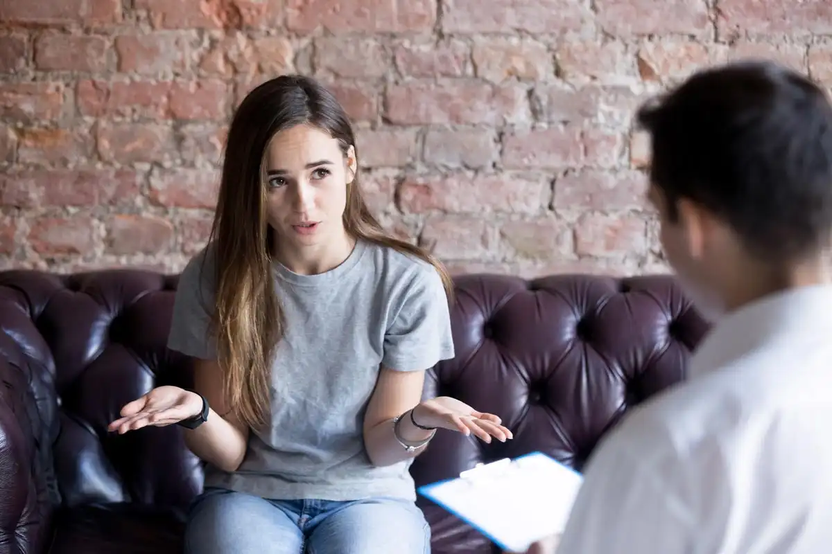 a photo of young lady talking to her psychologist complaining about her life