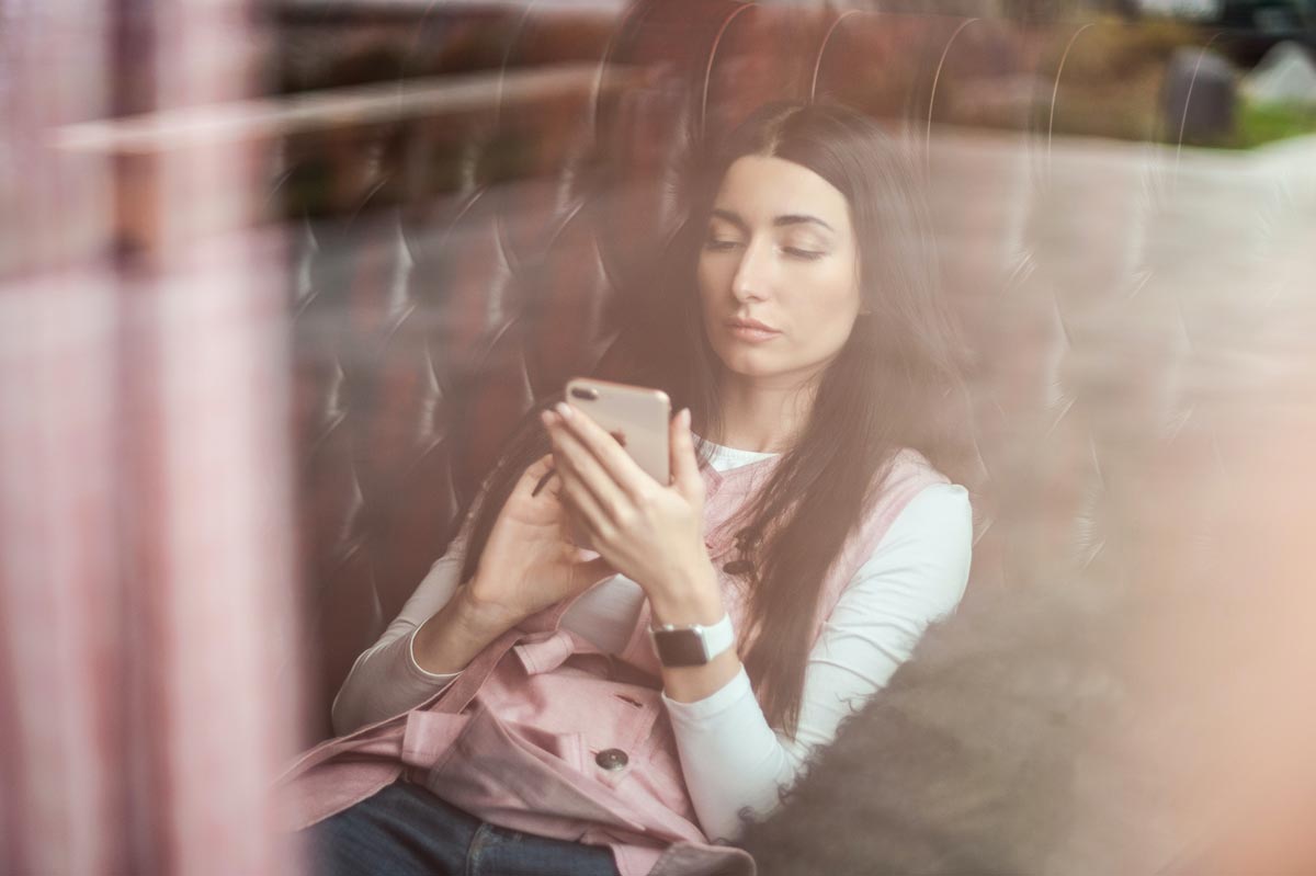photo of a sad woman with social anxiety issue using mobile phone