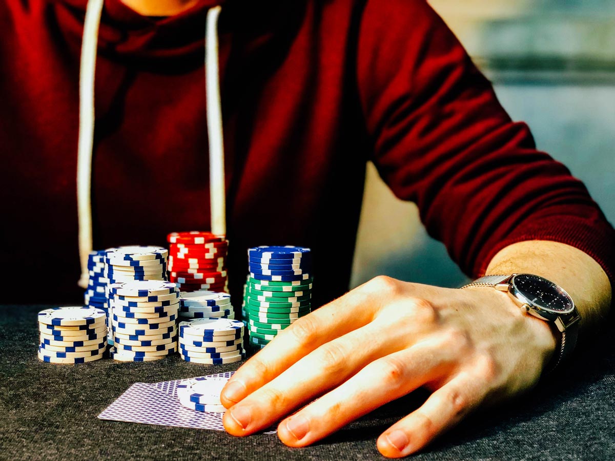 photo of a young man's hand holding some playing cards at the casino