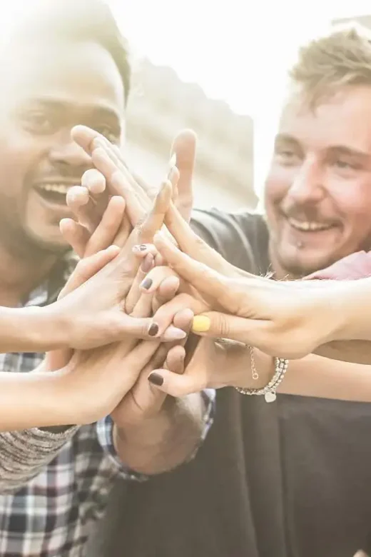 a photo of a young happy peers stacking hands outdoor celebrating together