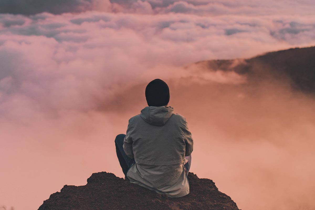 photo of a man meditating on top of the mountain