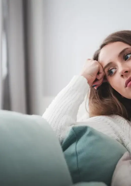 Sad woman sitting on sofa at home having negative thoughts
