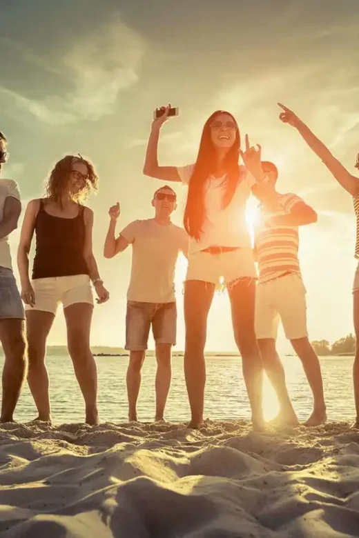 Friends funny dance on the beach under sunset sunlight