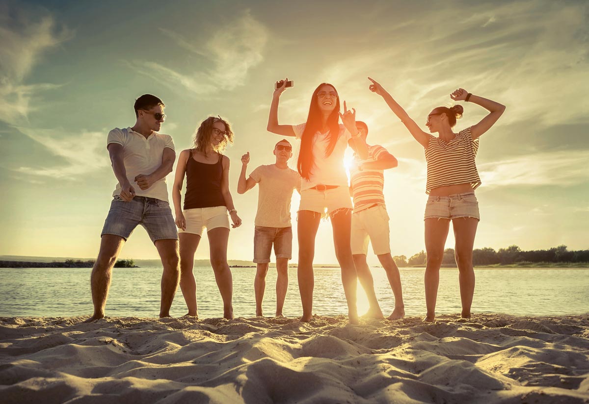 Friends funny dance on the beach under sunset sunlight