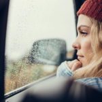 photo of Beautiful young female sitting on a car and looking outside the window