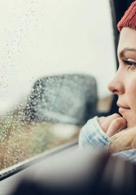 photo of Beautiful young female sitting on a car and looking outside the window