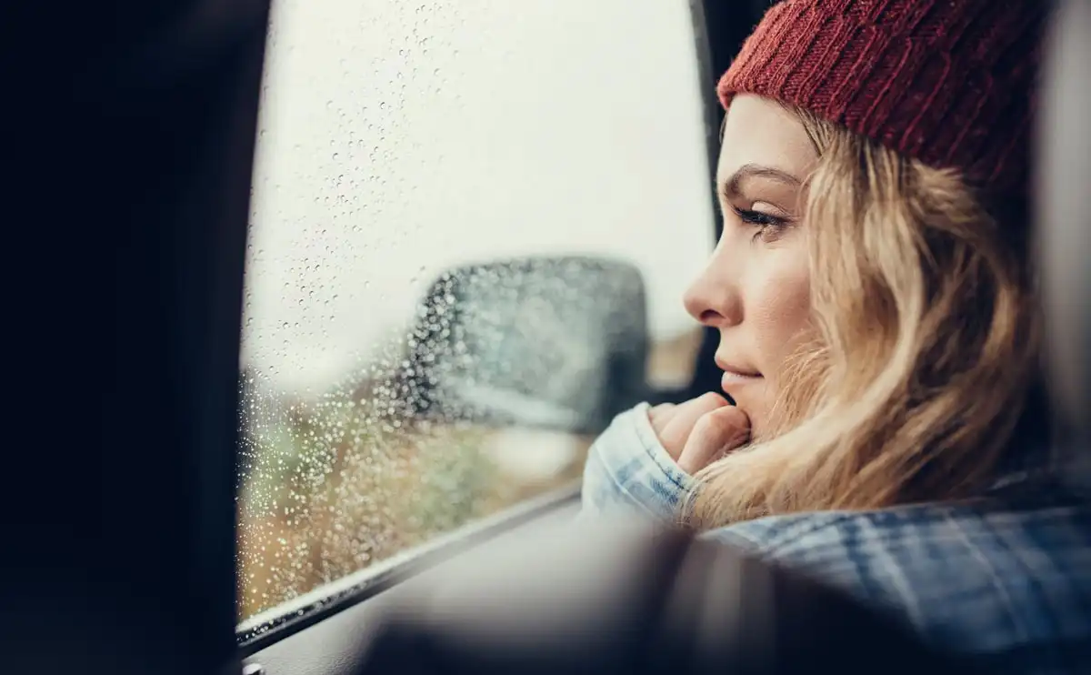 photo of Beautiful young female sitting on a car and looking outside the window