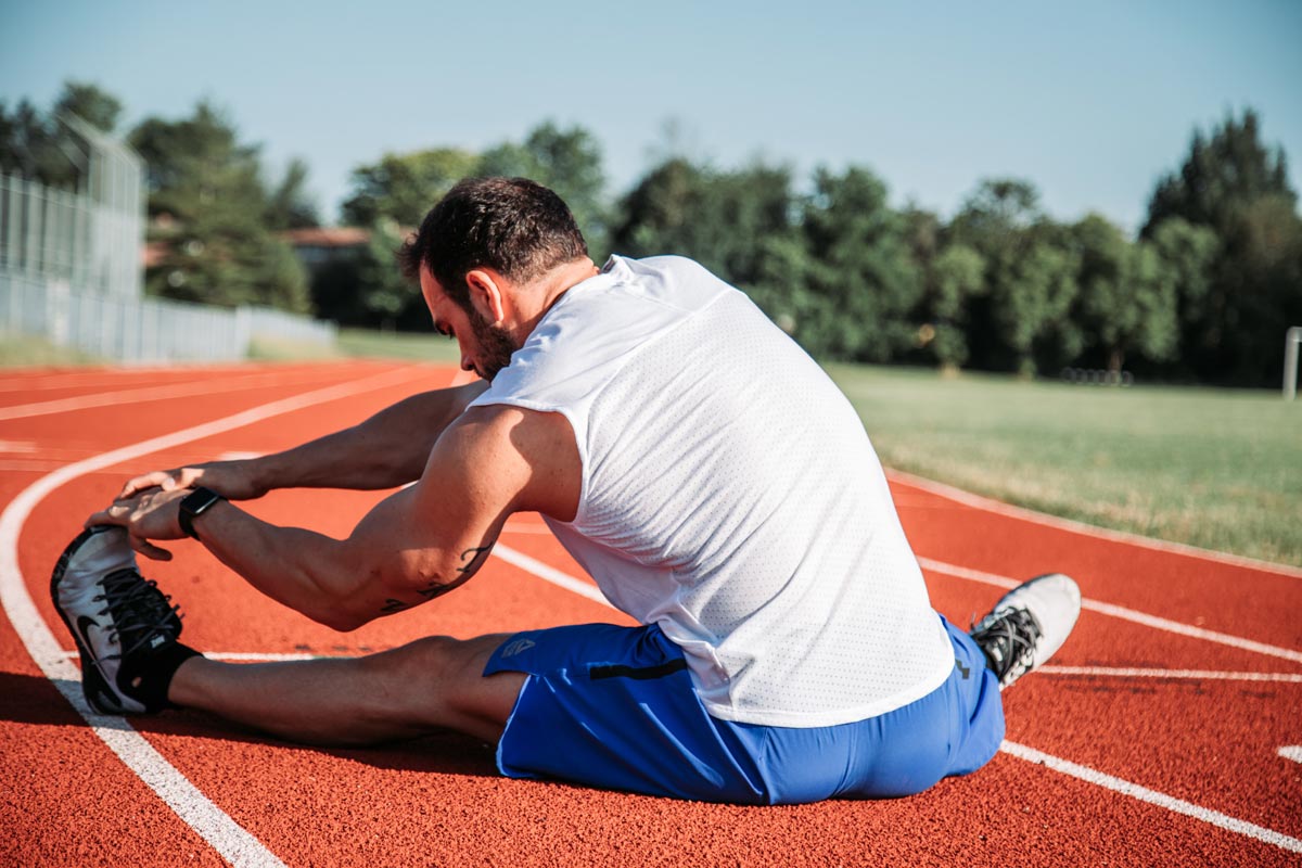 photo of a man stretching inside a track oval field