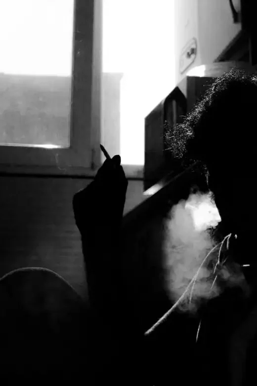 Addiction, Mental Illness and Cigarettes photo of a man smoking in a dark room