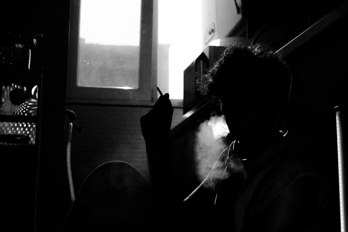Addiction, Mental Illness and Cigarettes photo of a man smoking in a dark room