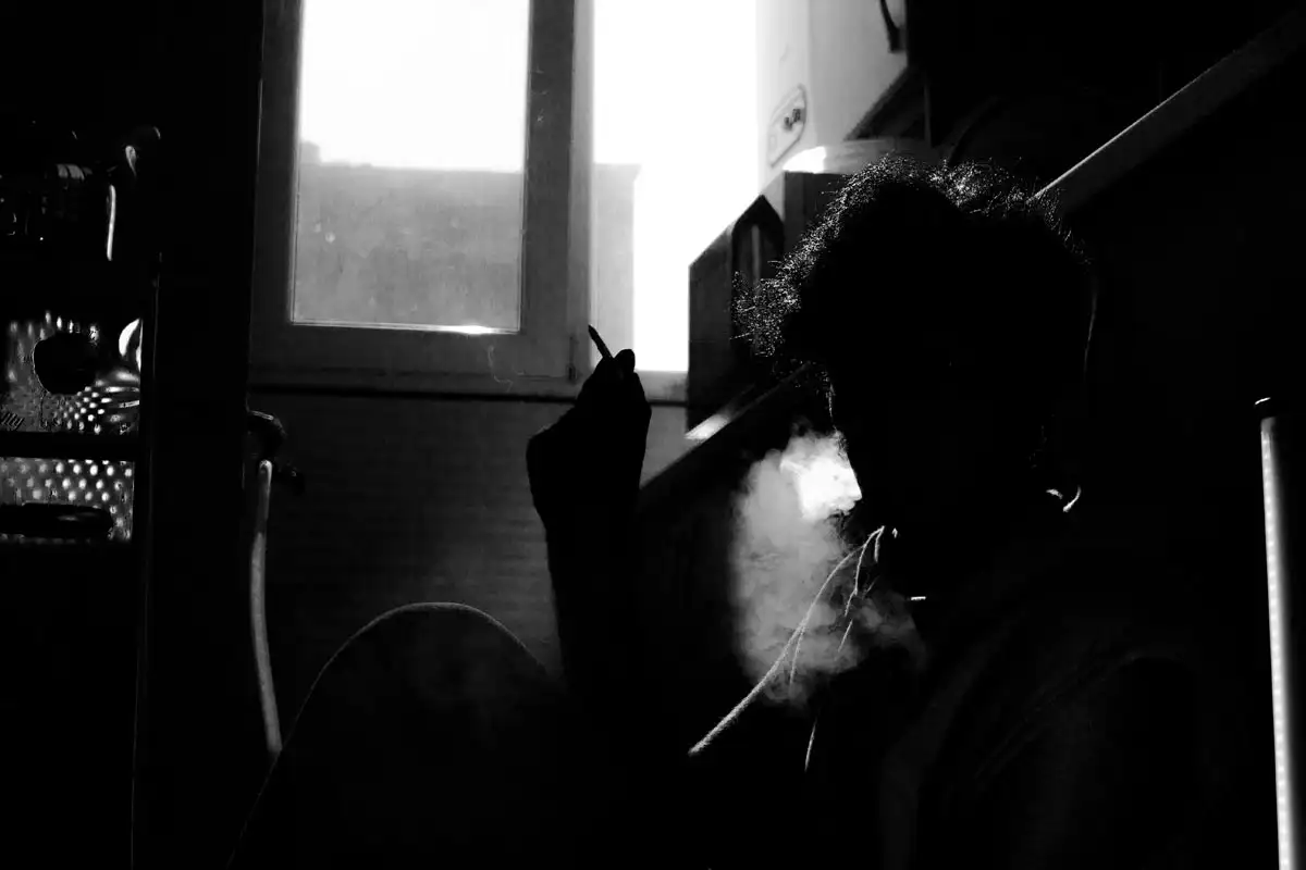Addiction, Mental Illness and Cigarettes photo of a man smoking in a dark room