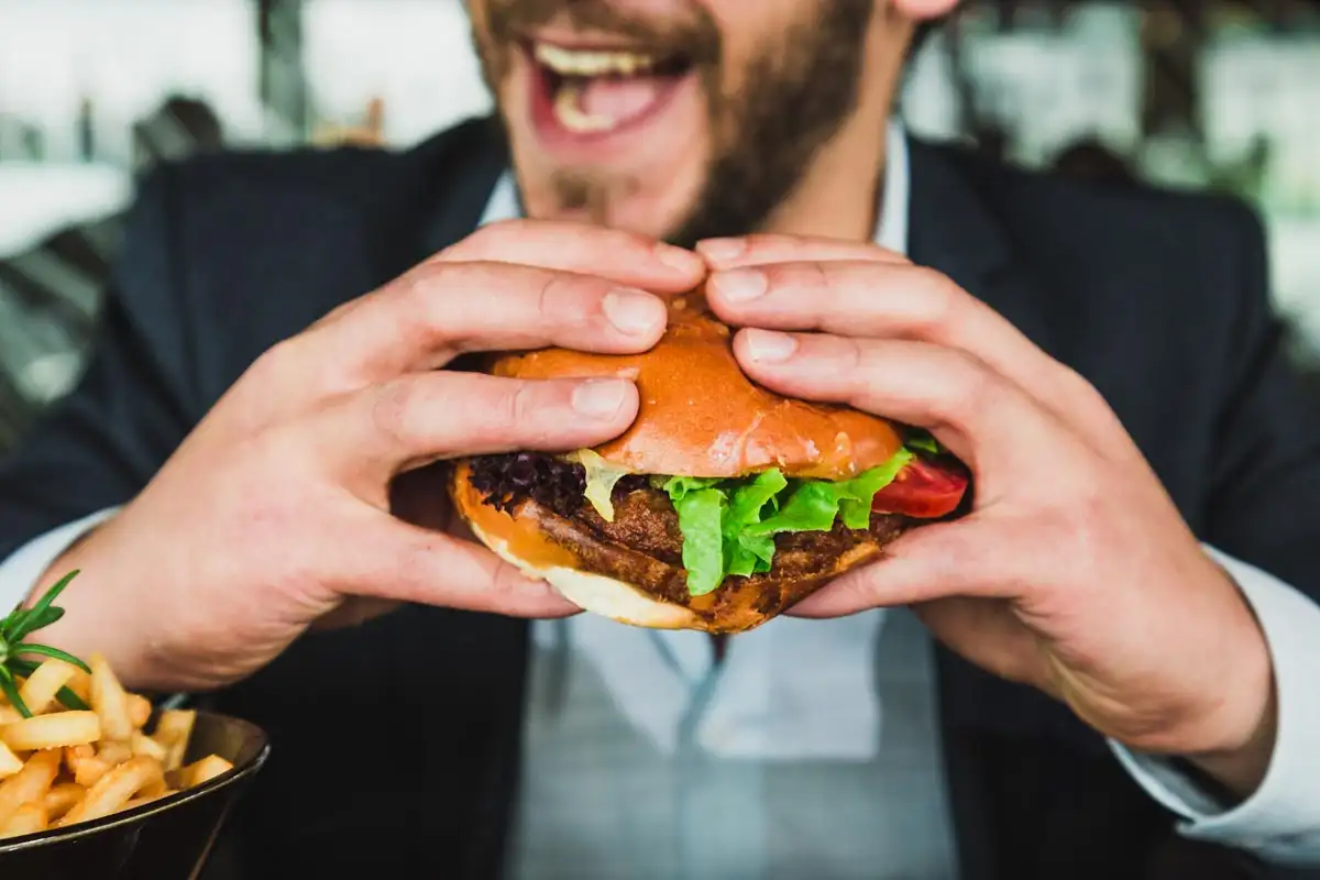 a photo of a man with eating disorder eating hamburger and fries