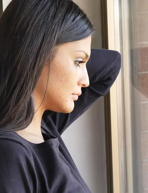 Photo of a Pretty Depressed Young Woman, Looking Down by a Window, Worried or Sad
