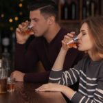Young couple drinking in bar with alcoholism problem