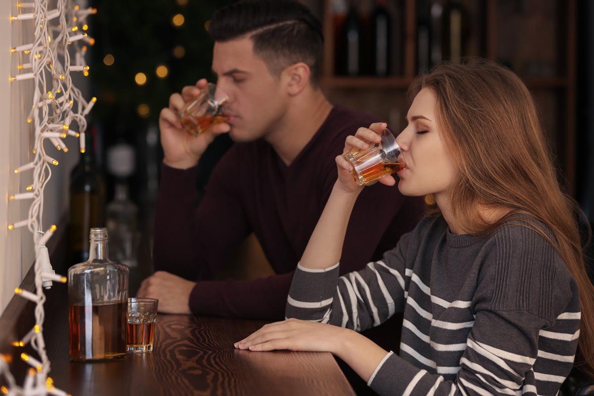 Young couple drinking in bar with alcoholism problem