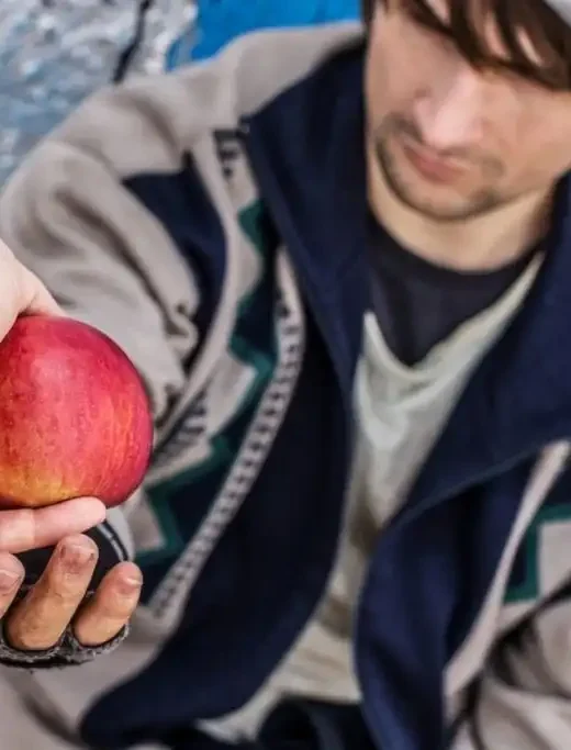 Homeless man receiving an apple
