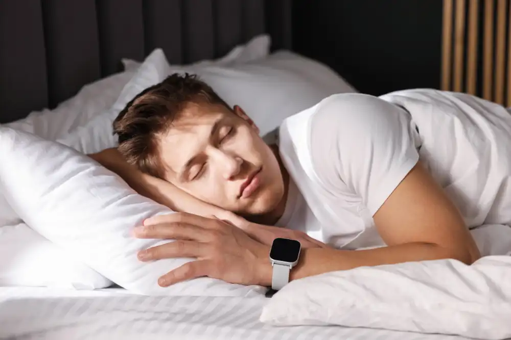 Young Man with Sleep Tracker Sleeping on Bed at Home