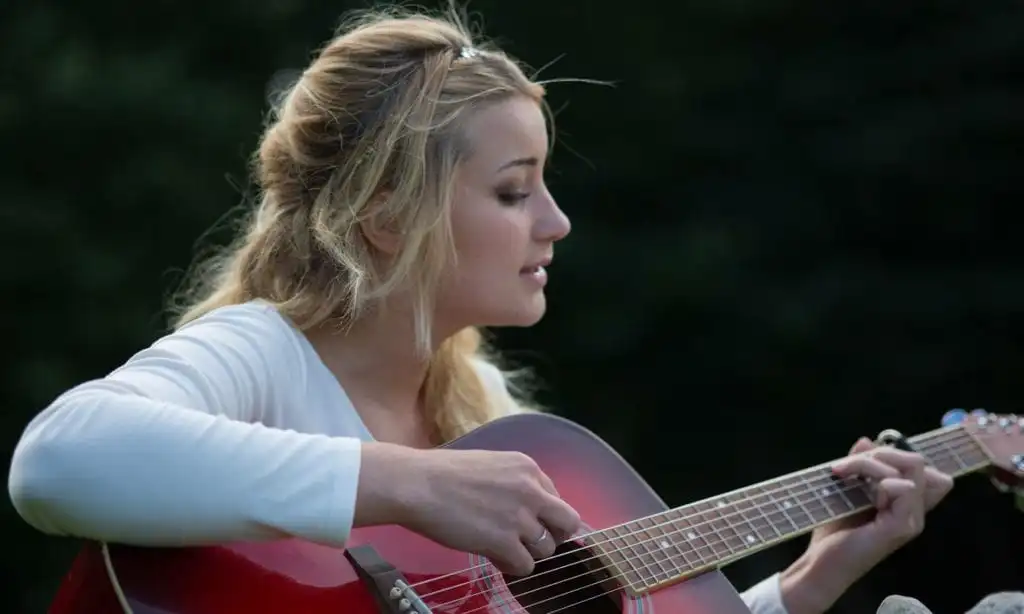 Young woman playing guitar, staying sober with addiction recovery