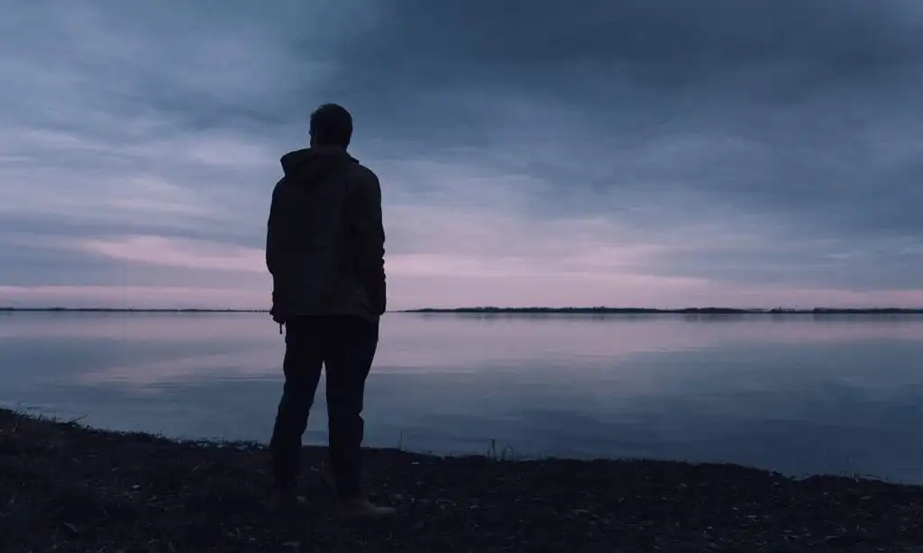 man near the lake grieving because of loss of a loved one while in recovery