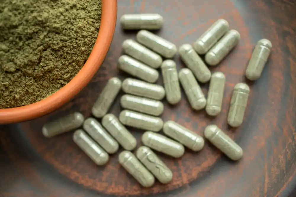 kratom supplement pills and kratom powder in the wood table