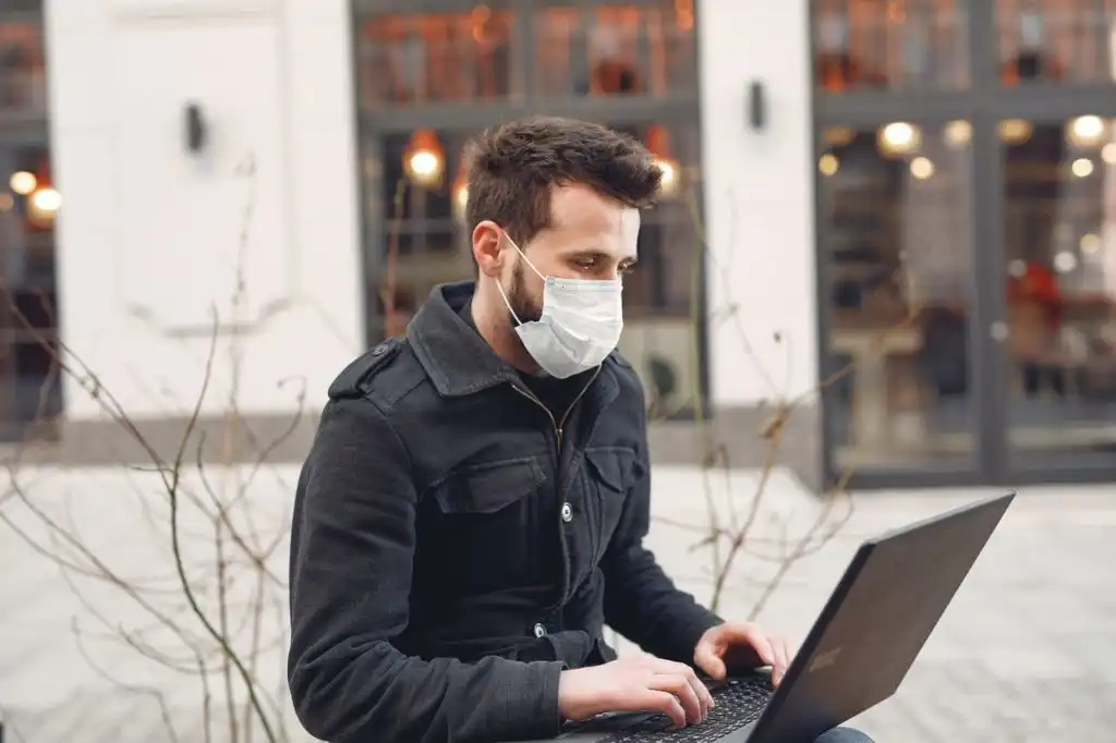 Man wearing a face mask participating in a drug counseling session online, like a Zoom meeting