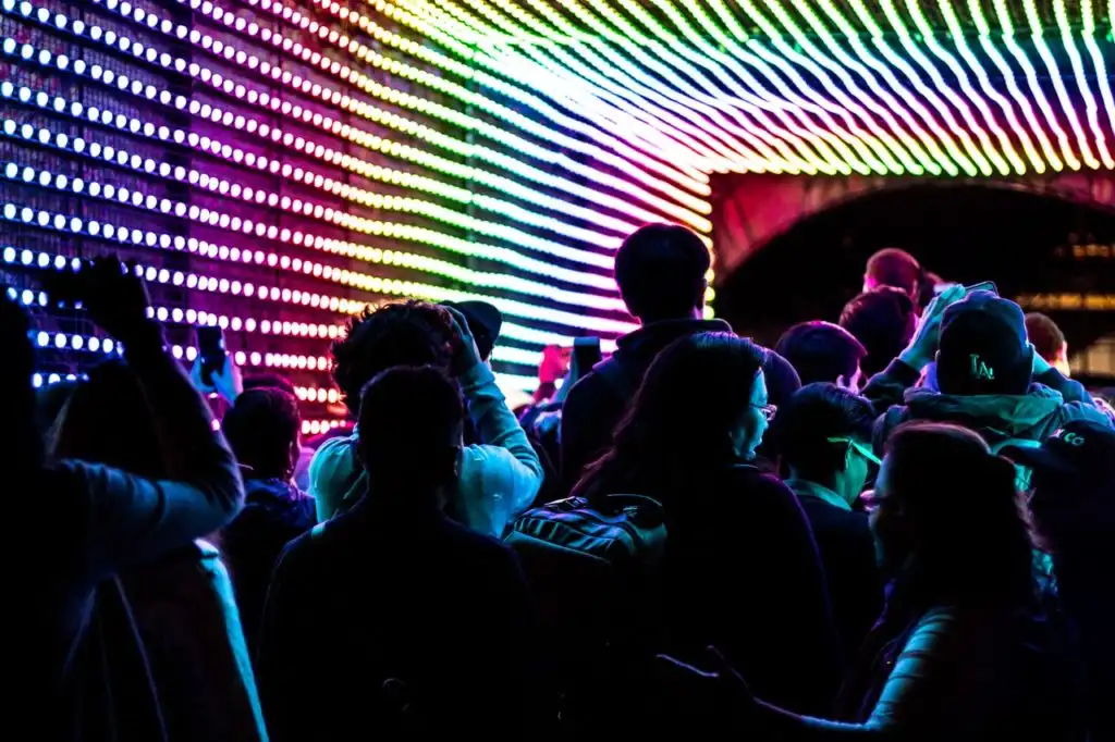 people at a concert with rainbow-colored light show catering to people who are on LSD or other psychedelic drugs