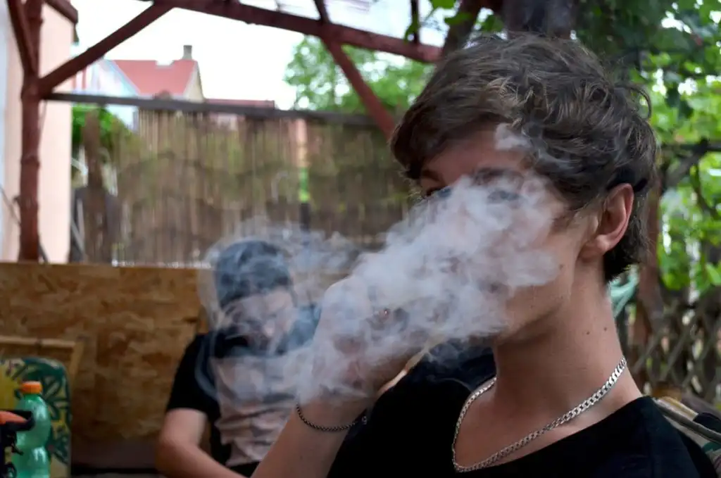Two young adults smoking weed outside