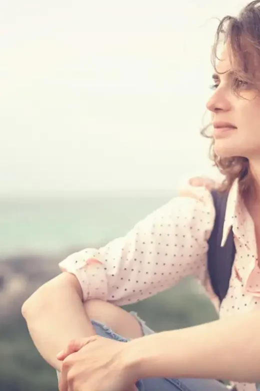 a beautiful young thoughtful beautiful girl sitting on the beach
