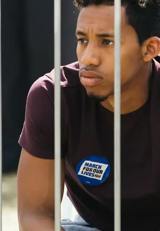 thoughtful man sitting behind metal fence thinking if he can avoid jail time if he goes to rehab