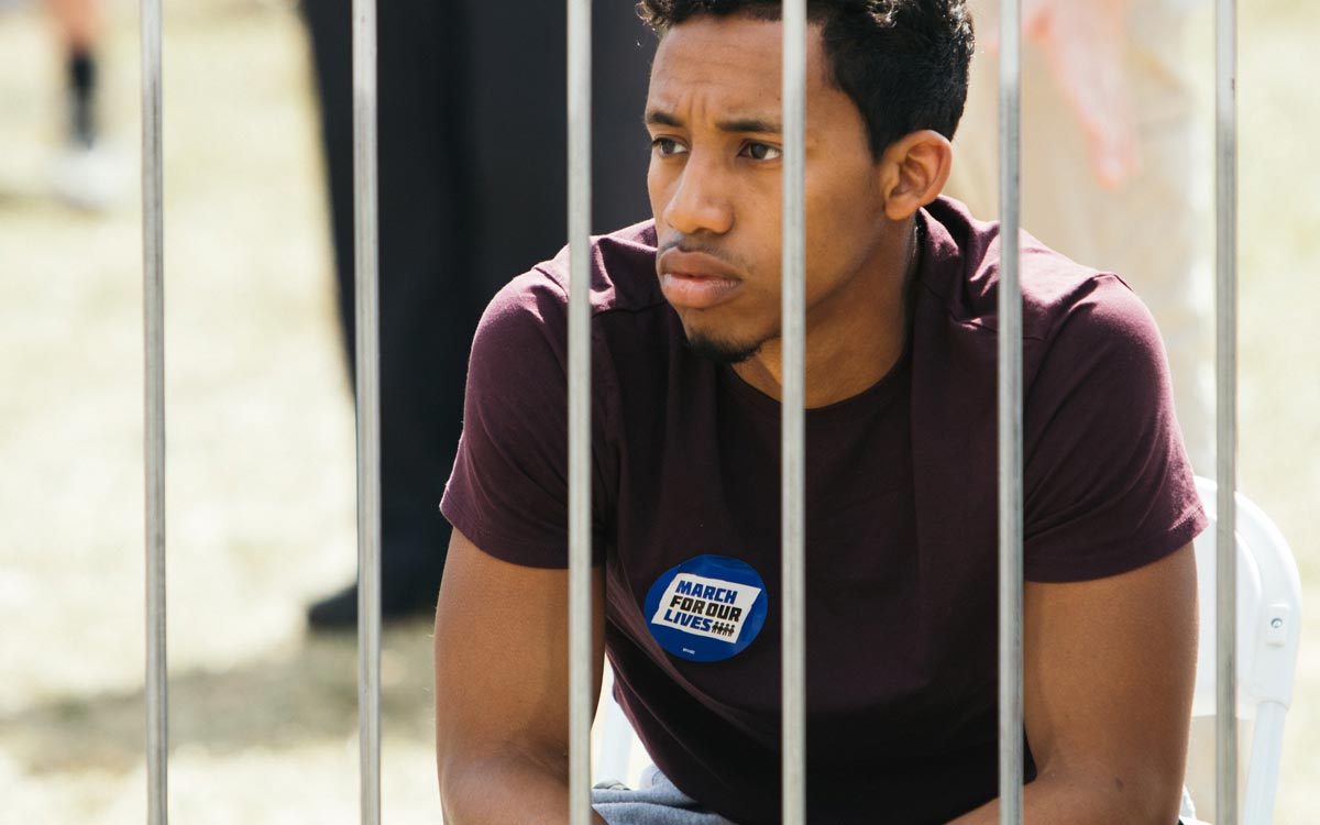 thoughtful man sitting behind metal fence thinking if he can avoid jail time if he goes to rehab