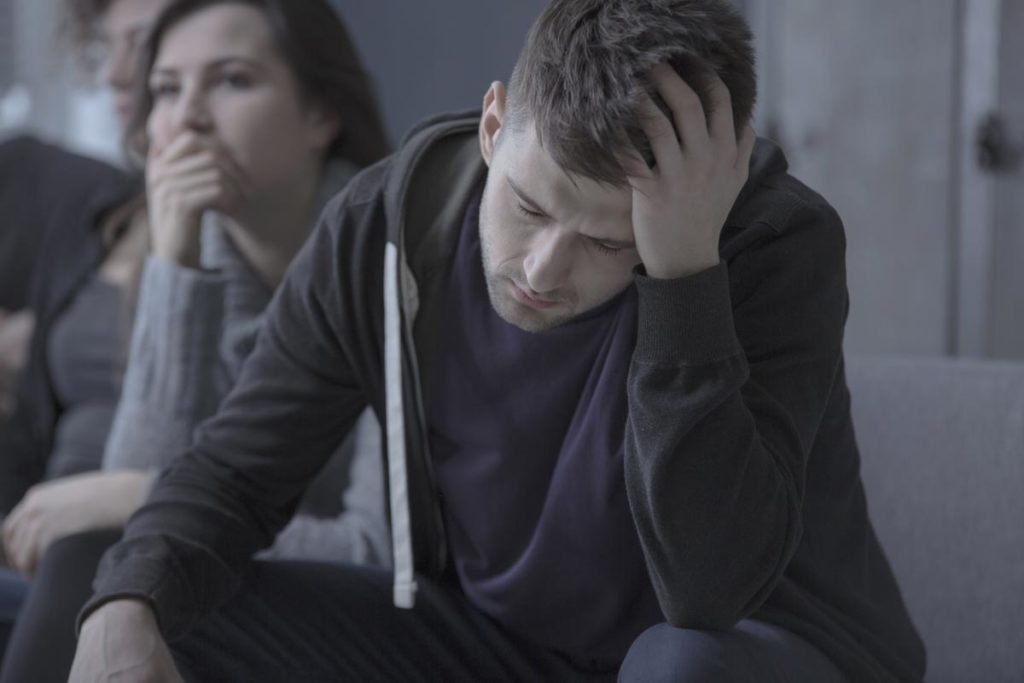 photo of depressed man with alcoholism problem sitting in dark rehab center