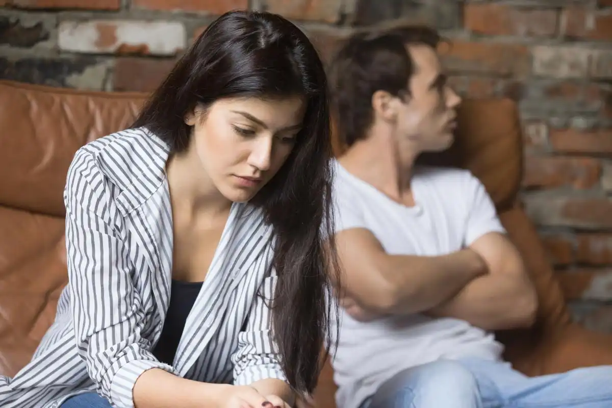 a sad young woman thinking of relationships problems sitting on sofa with offended husband