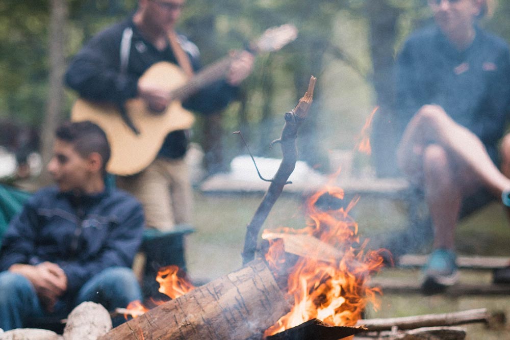 photo of friends camping and playing the guitar