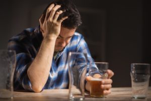 photo of a male alcoholic drinking beer from glass at night, alcohol addiction