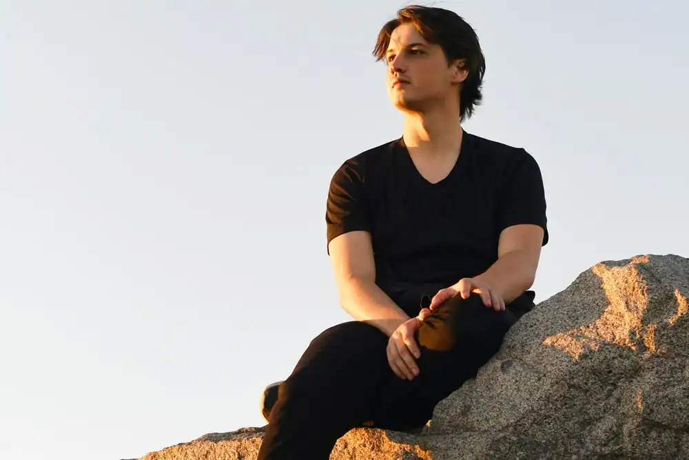 A man sitting on a rock looking into the distance at sunset