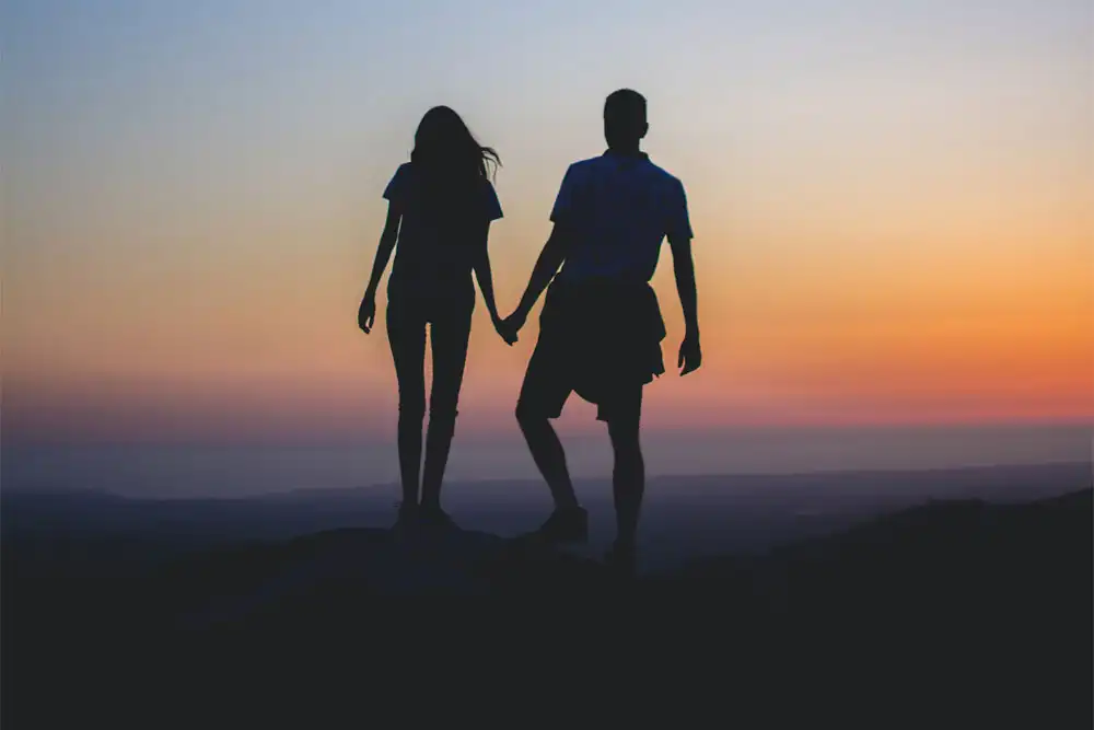 a couple holding hands on top of the mountain