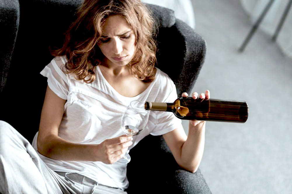 a woman holding a bottle of hard liqour suffering from alcohol abuse