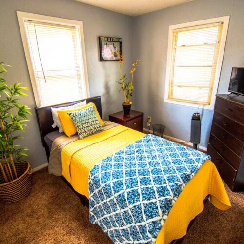 10 Acre Ranch BLU Private Cottages Facility Interior single bedroom with yellow bedsheet