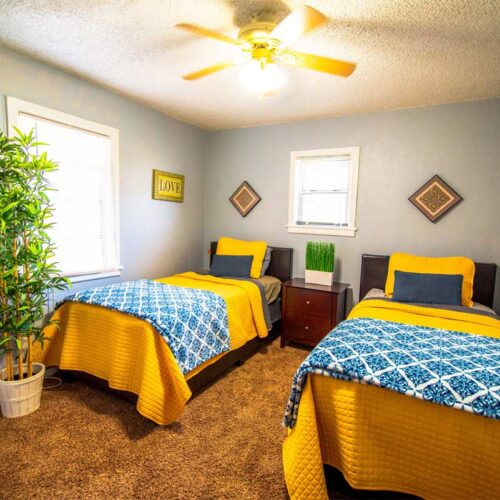 10 Acre Ranch BLU Private Cottages Facility Interior twin bedroom with yellow bedsheets