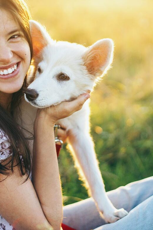 a female client sitting on a grass with her pet