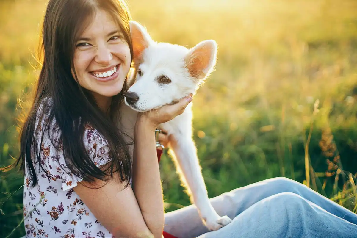 a female client sitting on a grass with her pet