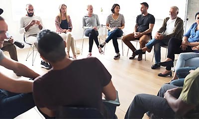 A diverse group of individuals engaged in a circle for group therapy in Los Angeles, California, fostering support and connection.