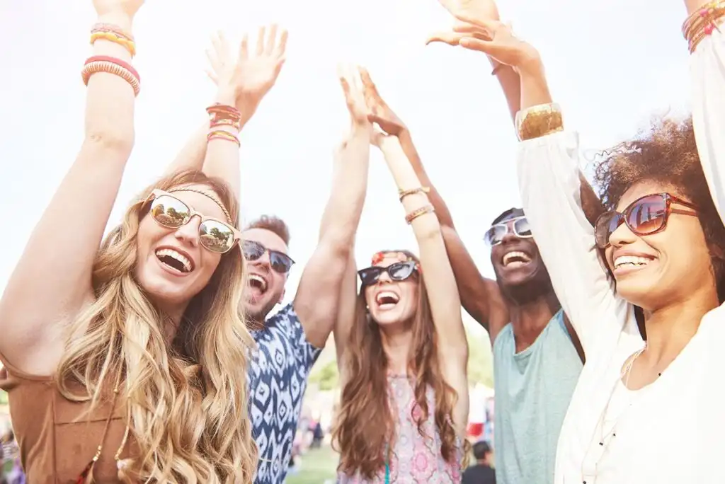 A diverse group of individuals with hands raised, celebrating progress in their recovery in a drug rehab in riverside california