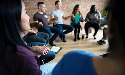 A group of individuals seated in a circle, engaged in discussion during a 12-step meeting in Los Angeles, California