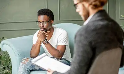 A man and a female psychotherapist are seated on a couch, participating in anger management treatment, therapy and education